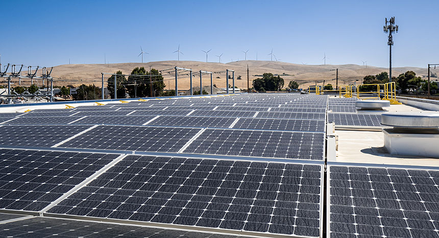 Solar panels with windmills in the background