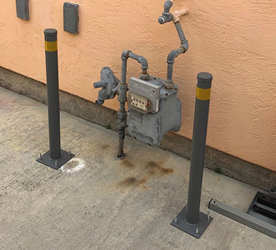 A pair of bollards on either side of a gas meter