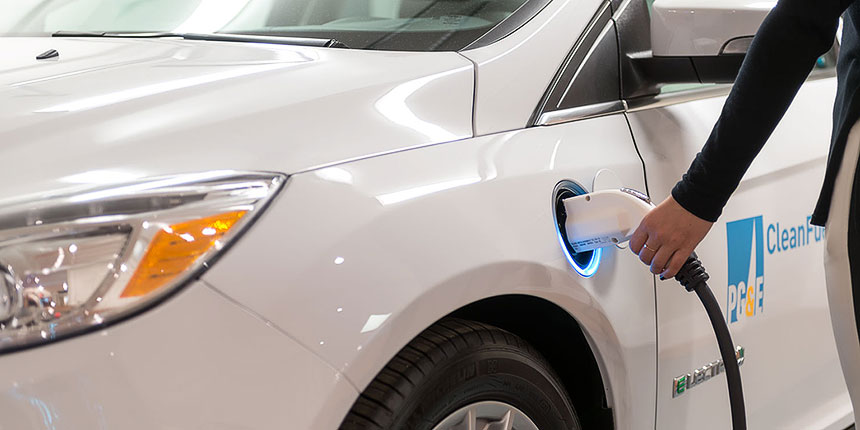 Person holding a charger to an electric vehicle