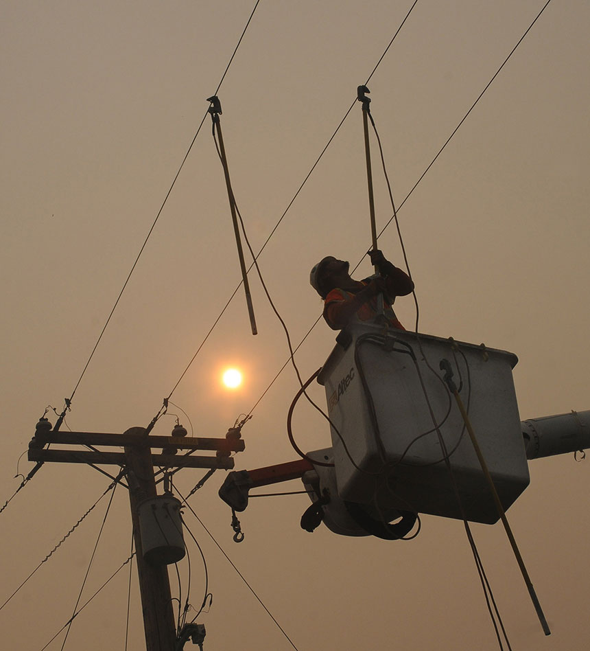 PG&E employee in a bucket working on overhead utility lines