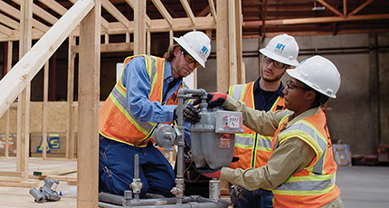 Three people working on a gas meter in a training facility