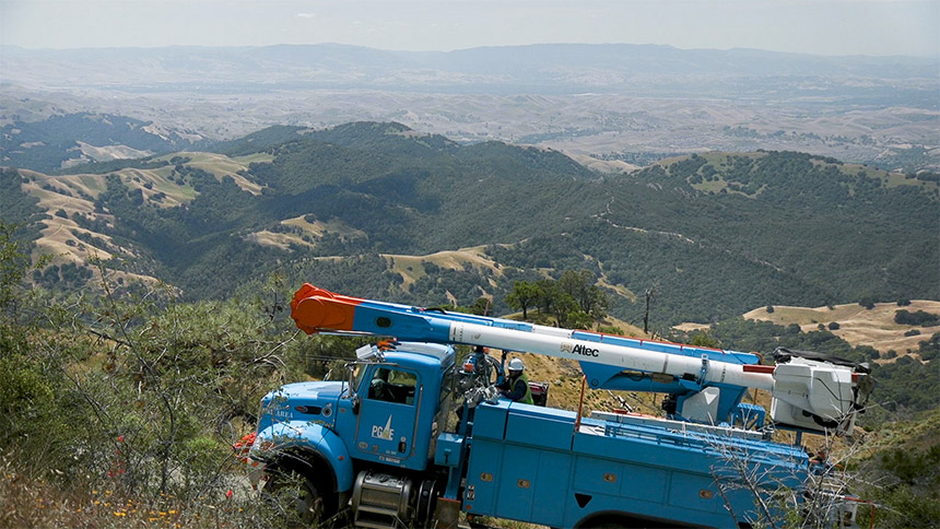 PG&E truck driving on a mountain road with mountains in the background